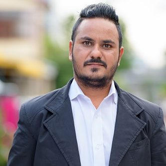 Portrait of bearded Indian businessman wearing suit in the streets outdoors
